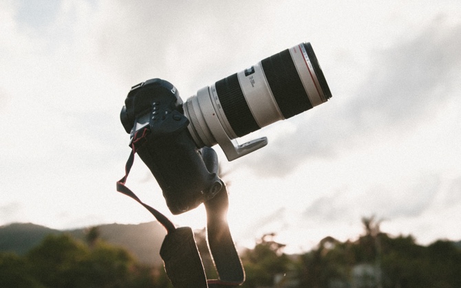 canon camera on a tripod with a long lens in front of a setting sun