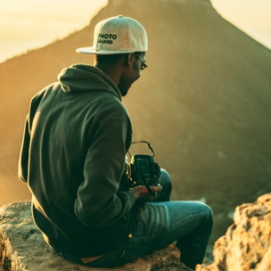 man sitting on a stony bench checking his camera